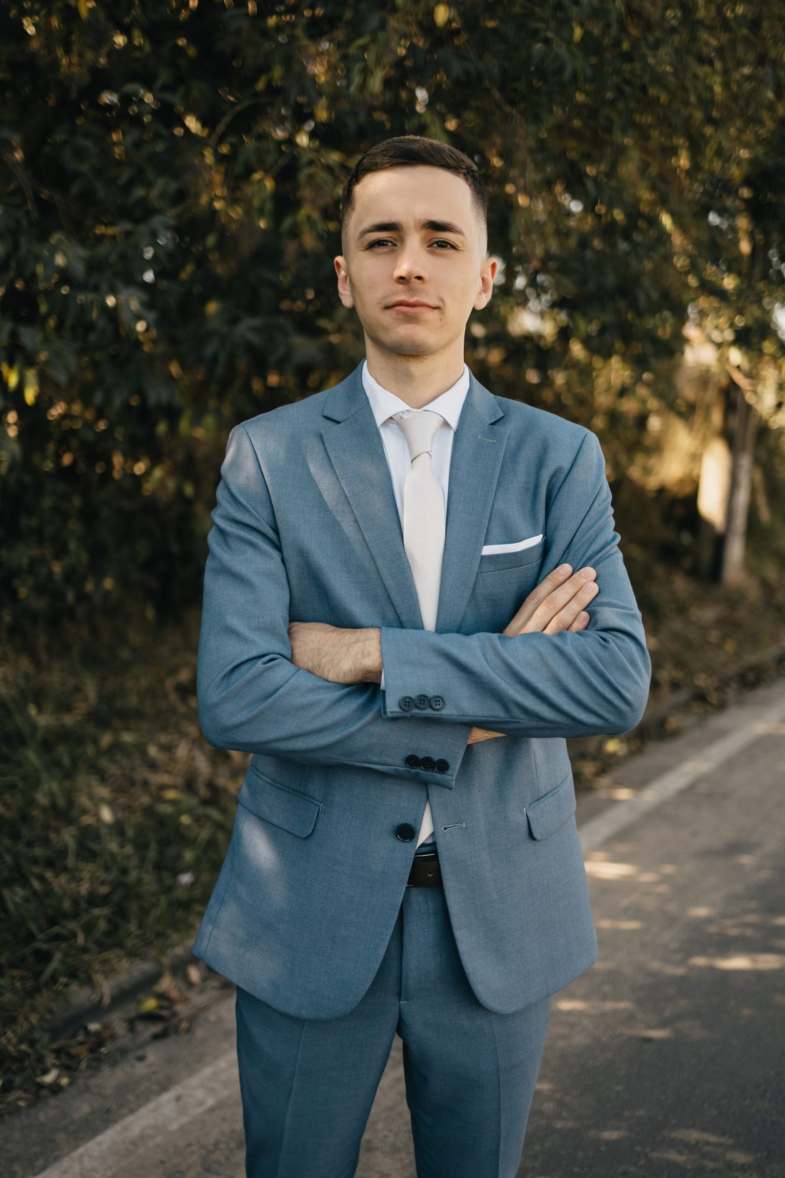 João Pedro de terno azul, de braços cruzados, olhando para a câmera